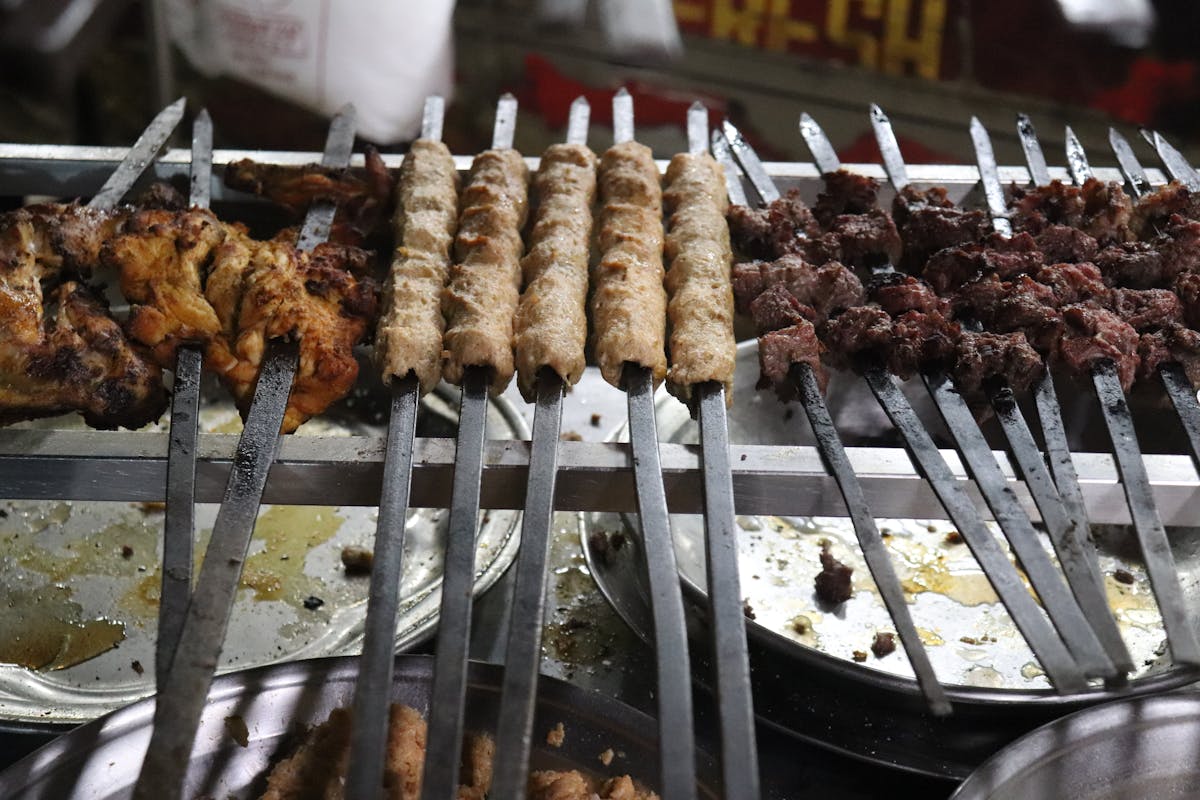 Pakistani seekh kebabs and chicken skewers grilling on a Karachi food street