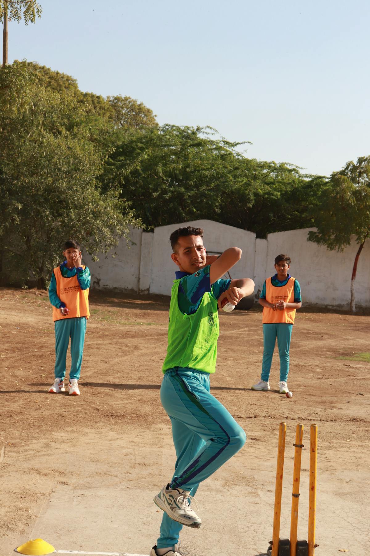 Young Pakistani cricketer in mid-bowling action on a Sindh ground