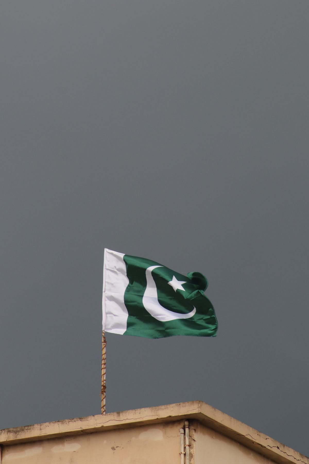 Pakistan national flag flying high against a stormy sky